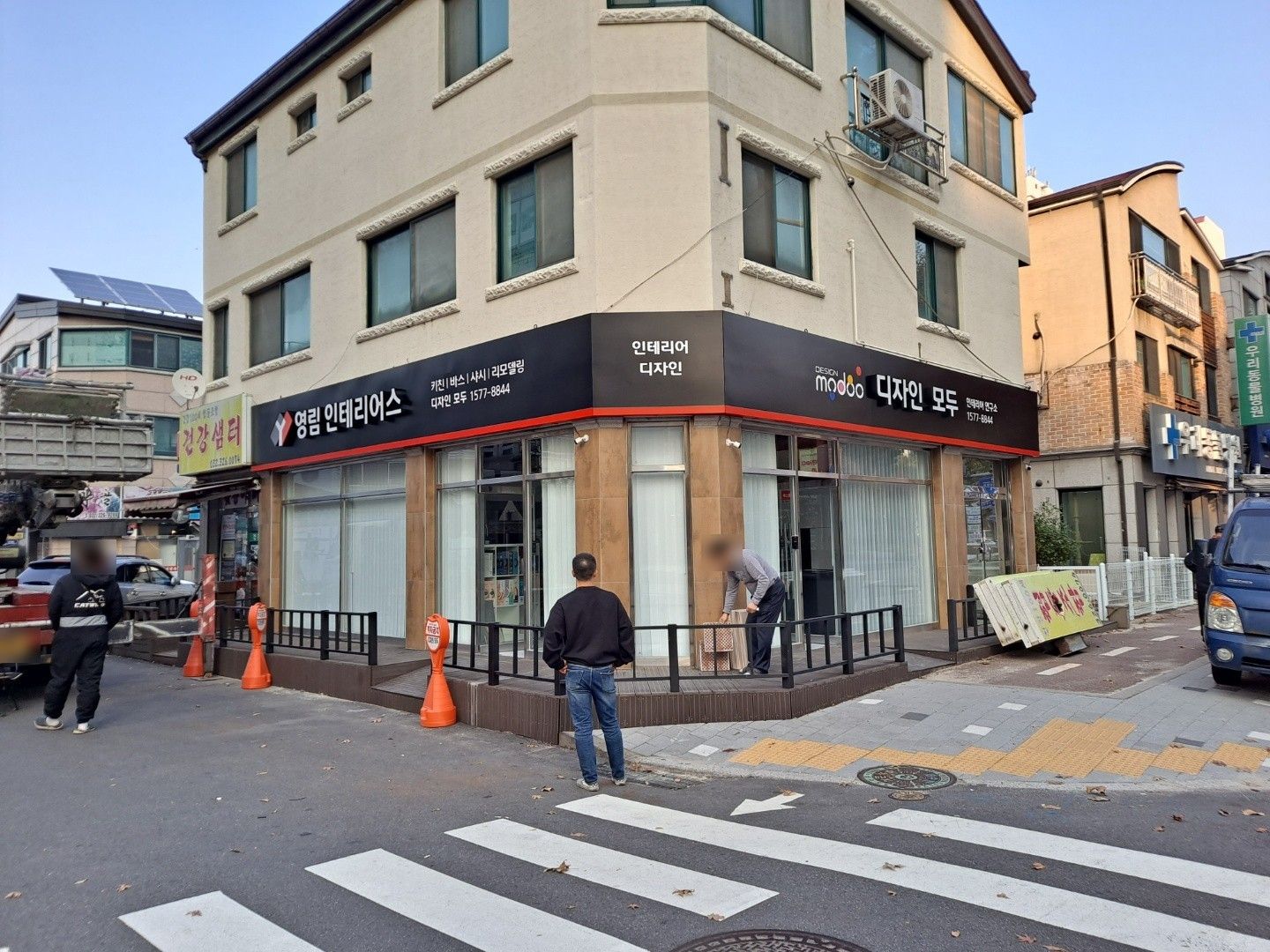 모서리 건물 1층을 두른 검정 바탕 붉은 띠 간판, 영림 인테리어스와 디자인 모두